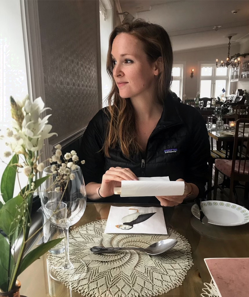 woman sitting at a table holding a sheet of paper and looking to the side